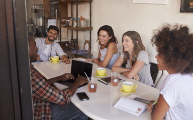 Young adult friends hanging out in cafe, seen through window