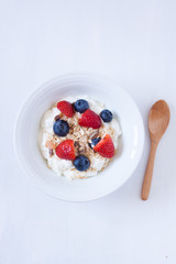 muesli with berries and yogurt on a white backgrund