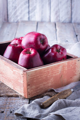 Ripe red apples in wooden box on table close up, copy space