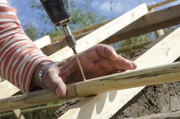 Male hands inserting a screw in the construction with a drill