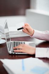 Close up of business woman hands using credit card and laptop computer