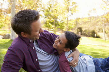 Fototapeta premium Father and son lying down embracing in a park