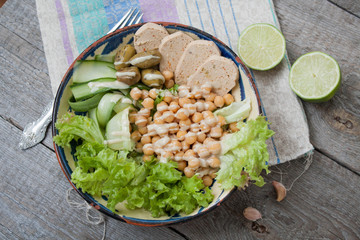 healthy salad in a bowl. olives, lime, chickpeas, cucumber  and tahini. more greens every day