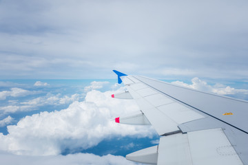 Wing of an airplane flying  above white cloud