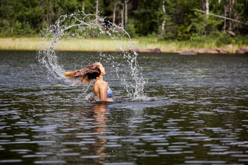 Beautiful girl splashing her hear in an Swedish forest lake