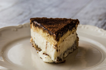 Homemade Tiramisu Cake on a white wooden surface.