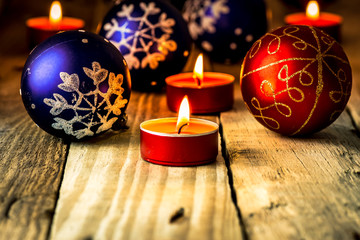 Christmas blue and red balls with lit candles on distressed wood background, greeting card template 