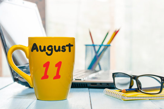 August 11th. Day 11 of month, morning yellow coffee cup with calendar on freelance workplace background. Summer time. Empty space for text
