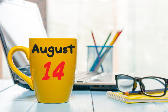 August 14th. Day 14 of month, morning yellow coffee cup with calendar on IT-office background. Summer time. Empty space for text