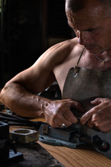 Muscular Middle Aged Artisan working with Metal Vise at his Workshop