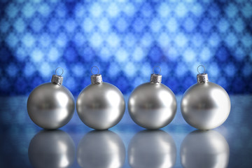 Four silver baubles on blue background