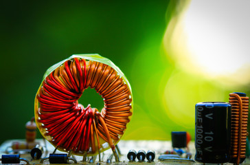 Electromagnetic coil, inductor. Small winding coils and fuse are mounted on a baseplate. Background on Morning sun.