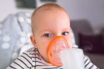 Little girl is taking inhalation therapy by the mask of a nebuliser