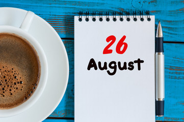 August 26th. Day 26 of month, loose-leaf calendar on blue background with morning coffee cup. Summer time. Top view