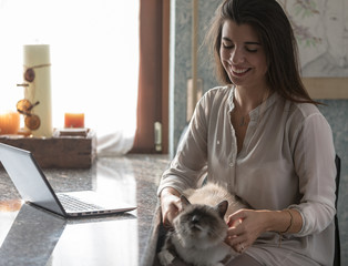 Smiling happy woman caressing her pet cat
