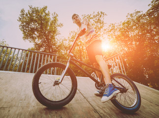Boy stands with his bmx in a park.