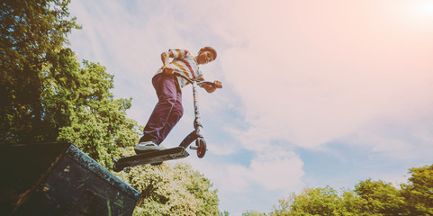 Boy riding a kick scooter in a park