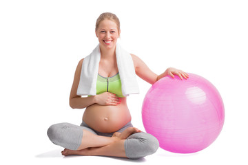 Happy and pregnant woman sitting in lotus position with medicine ball