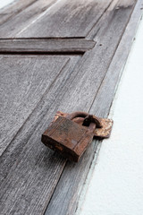 Old rusty padlock on old wooden door.