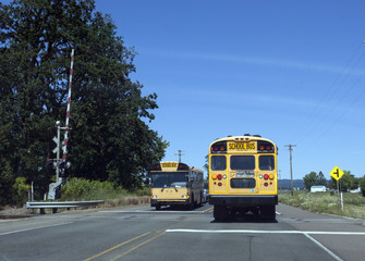 Fototapeta na wymiar School Buses at Railroad Crossing