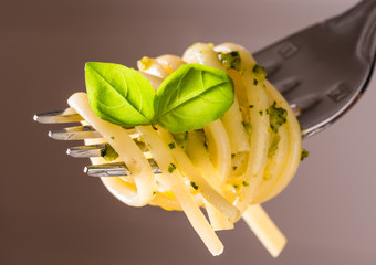 Pesto pasta, spaghetti on fork with basil pesto sauce.