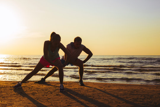 Fitness couple stretching in sunset