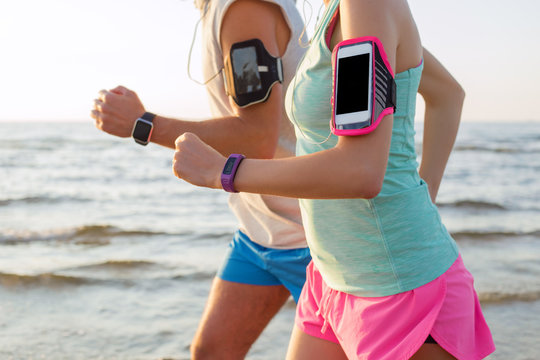 Couple running on the beach with their mp3 players