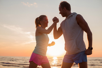 Fit and happy couple on the beach showing their strength