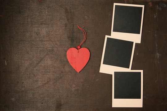 Retro Vintage empty Photo frames and red wooden heart on old dark Background. Top view with copy space. Toned 