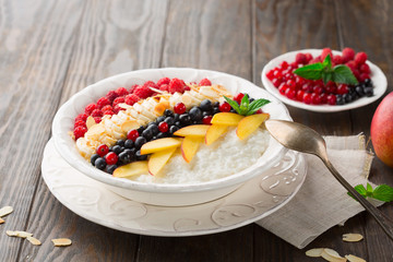 Rice pudding with fresh fruits, rustic wooden table