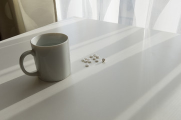 Fototapeta na wymiar white pills lying next to a glass of water on a wooden table