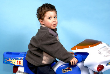 Toddler boy excited to be on toy motorcycle