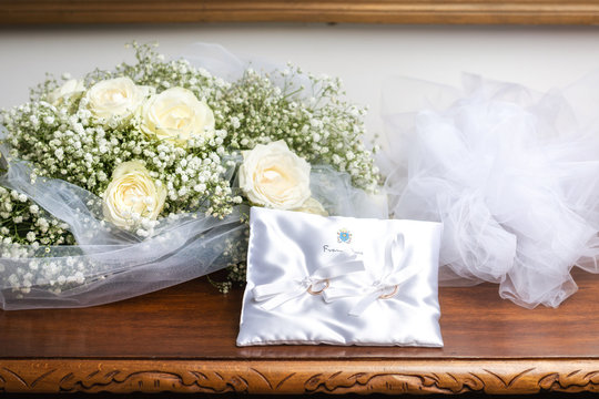 Bouquet sposa e cuscino porta fedi appoggiati su un tavolo in legno