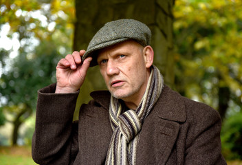Portrait image of a mature man in a hat and scarf outdoors 