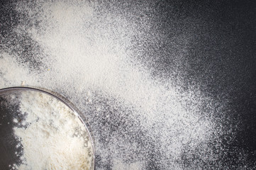 Sieve with a flour. On a black background.Top view. Flat lay.