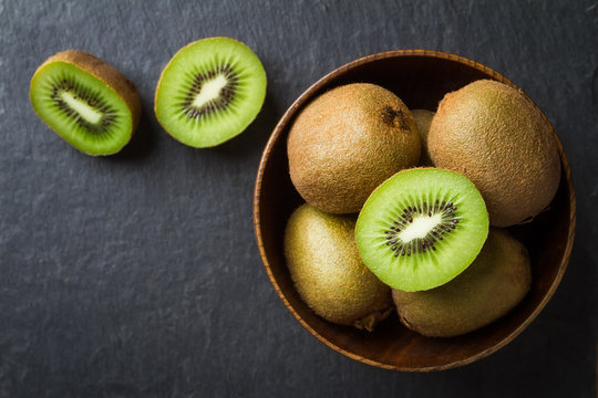 Fresh kiwi in a wooden bowl on a black