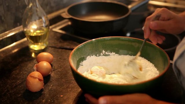 Slow-motion footage of a cook mixing flour with eggs to make dough for pancakes