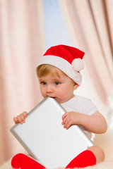 Baby santa holds a tablet