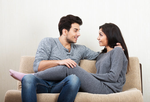 Young happy couple talking each other sitting on a sofa