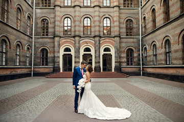 Obraz premium Wedding couple stands on the old grey backyard