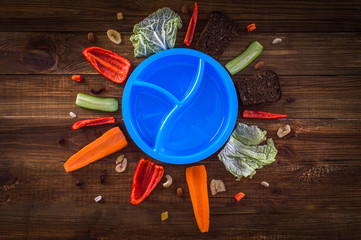 Divide breakfast ingredients. Lay a circle around a lunch box. On a wooden background.