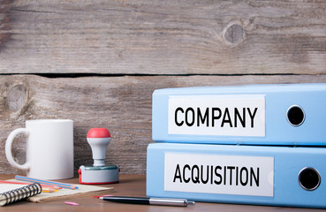 Company and Acquisition. Two binders on desk in the office. Busi