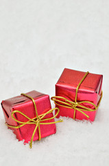 Red gift boxes on Snow background / two small red, metallic bright parcels on snow background, close up, space for text, horizontal 