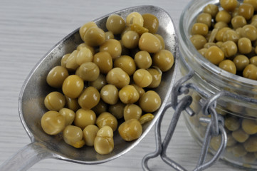 Cuillère de petits pois au-dessus d'un bocal de petits pois