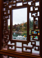 View through a detailed Chinese  window in a Pagoda out at the beautifully landscaped ornamental Chinese Garden
