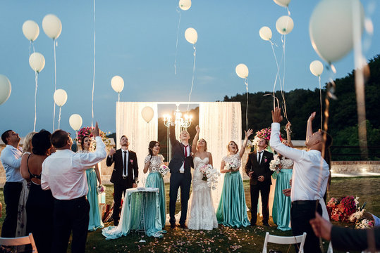 Newlyweds and their friends pull balloons in the air after the c