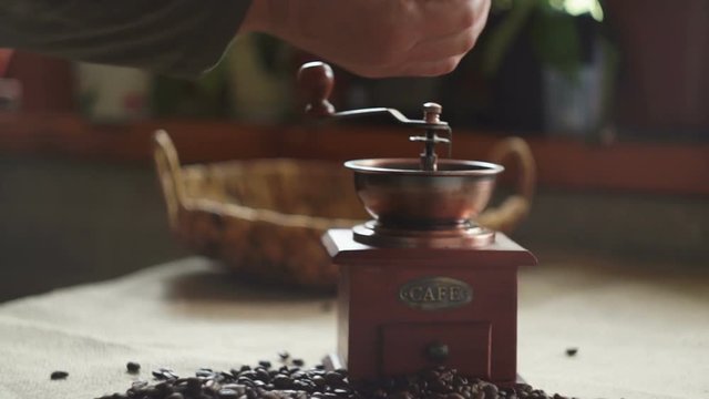 Woman puts coffee beans in an antique coffee grinder. Slow motion