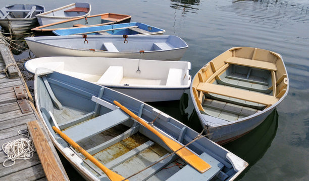 Small Boats at a Dock:  Several rowboats tied to a wooden pier sit quietly on bay in Maine.
