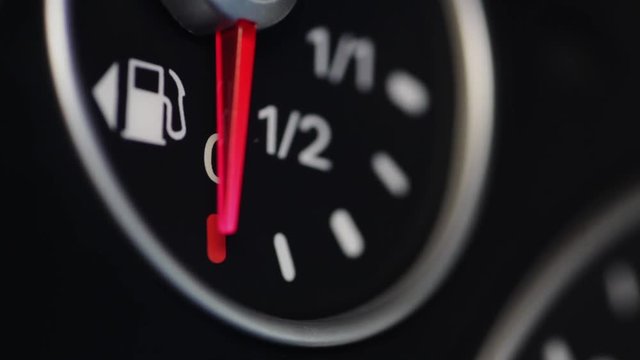 Color close up footage of a car's fuel gauge with the needle moving.