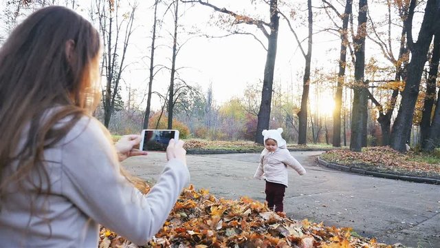Mother makes footage of baby at autumn park, mobile phone